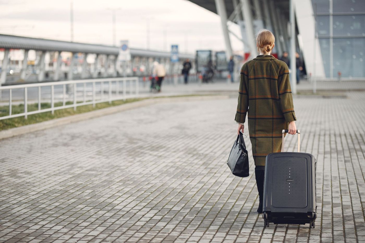 Traveller with luggage outside the airport terminal, ready for a chauffeur pickup